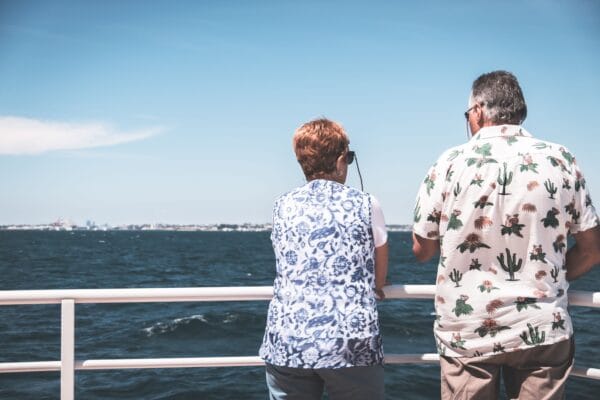 Two senior travellers man and woman on cruise ship looking out to sea with health conditions