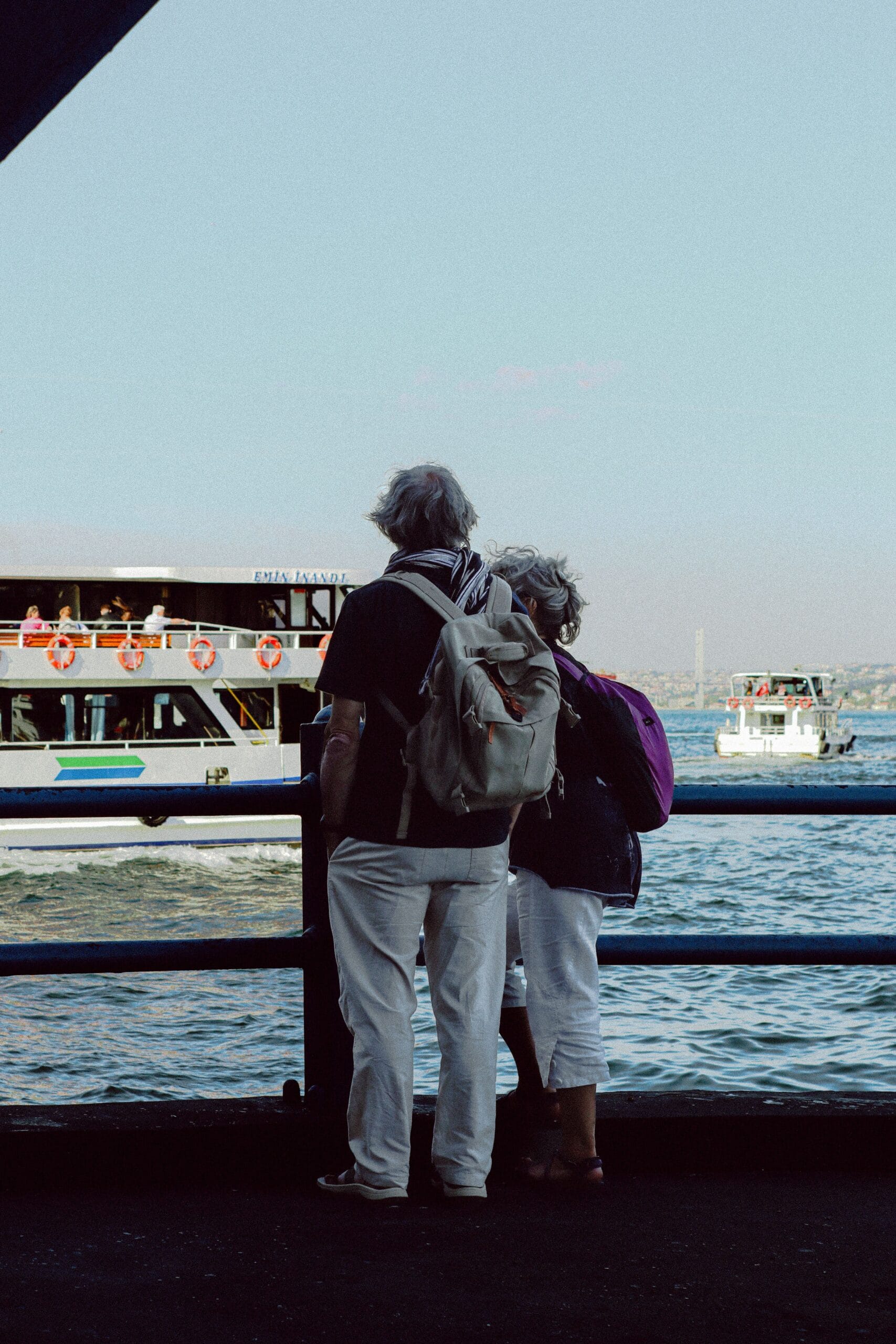 Cruising with diabetes, Elderly couple stands by the waterfront watching boats on a sunny day.