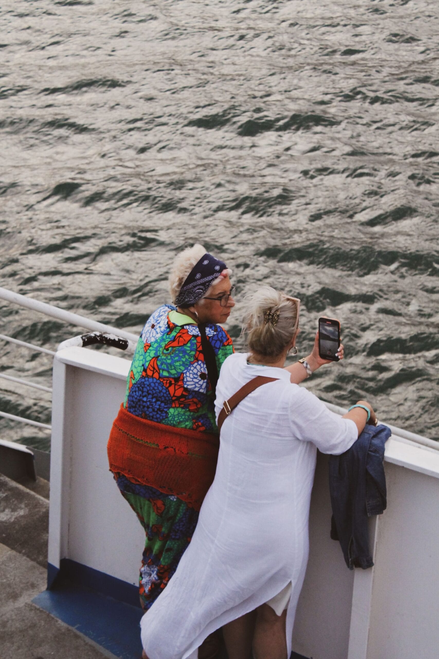Cruising with sleep apnoea and a CPAP machine, Two women taking photos on a ferry with a smartphone view of a river, ocean, sea