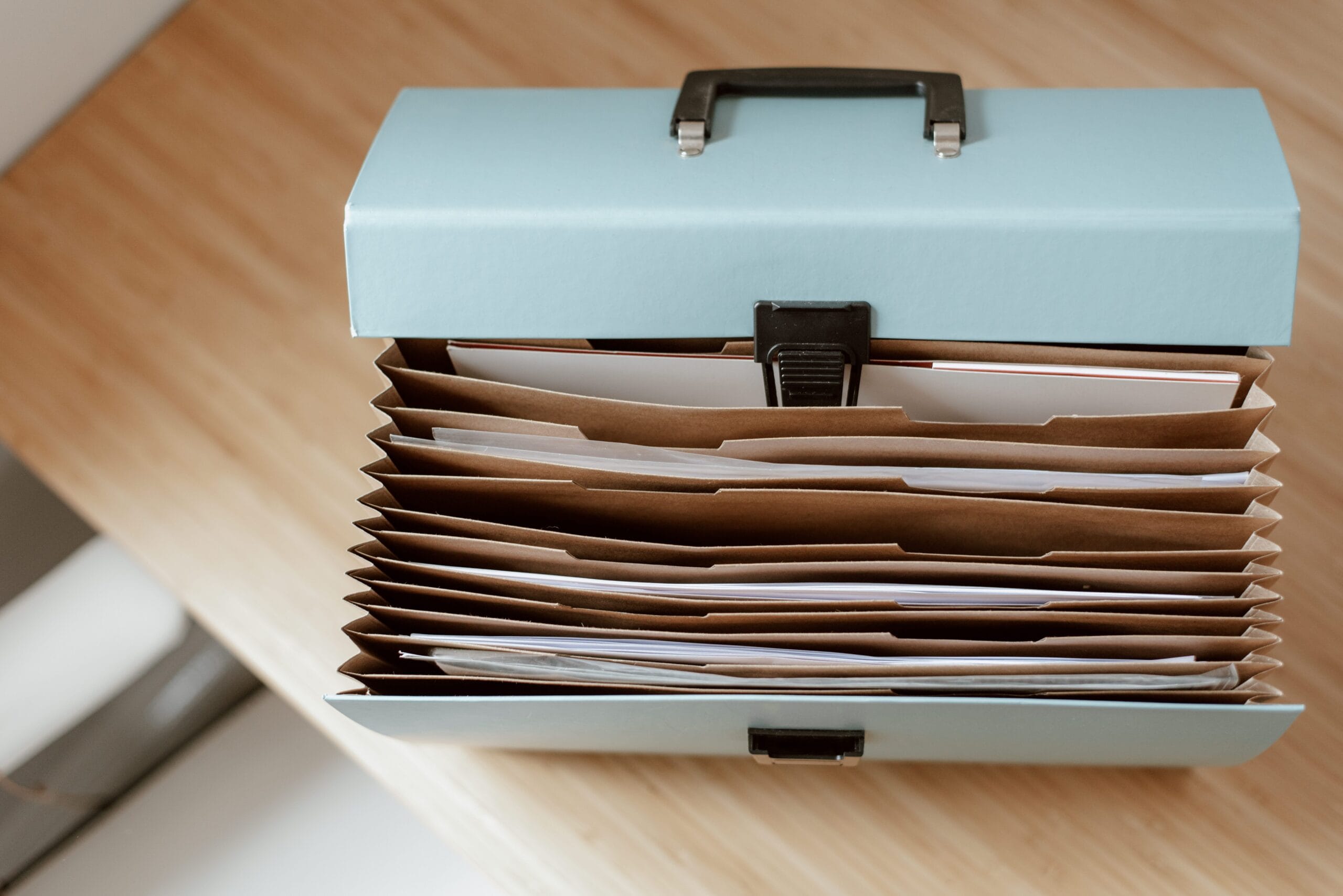 Doctor's Letters for Travel: What They Should Say, A top-down view of a blue accordion folder filled with organized office documents on a wooden desk.