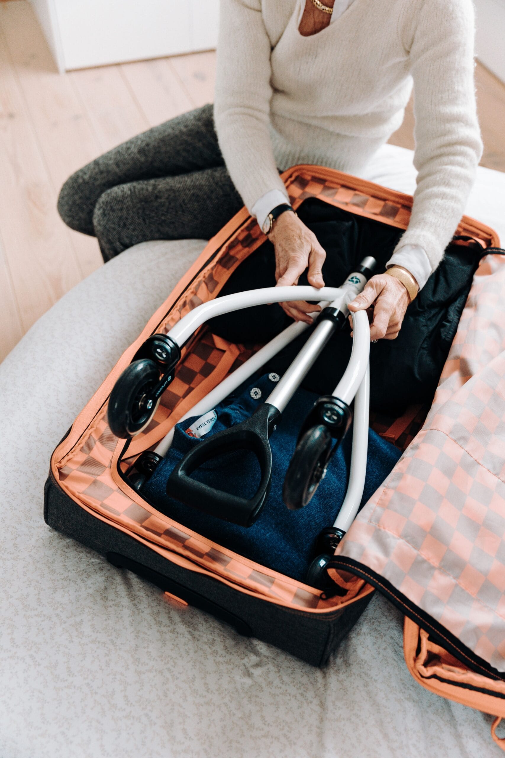 Flying With a Wheelchair: A Complete Guide, Senior woman packing lightweight rollator into an open suitcase for travel.
