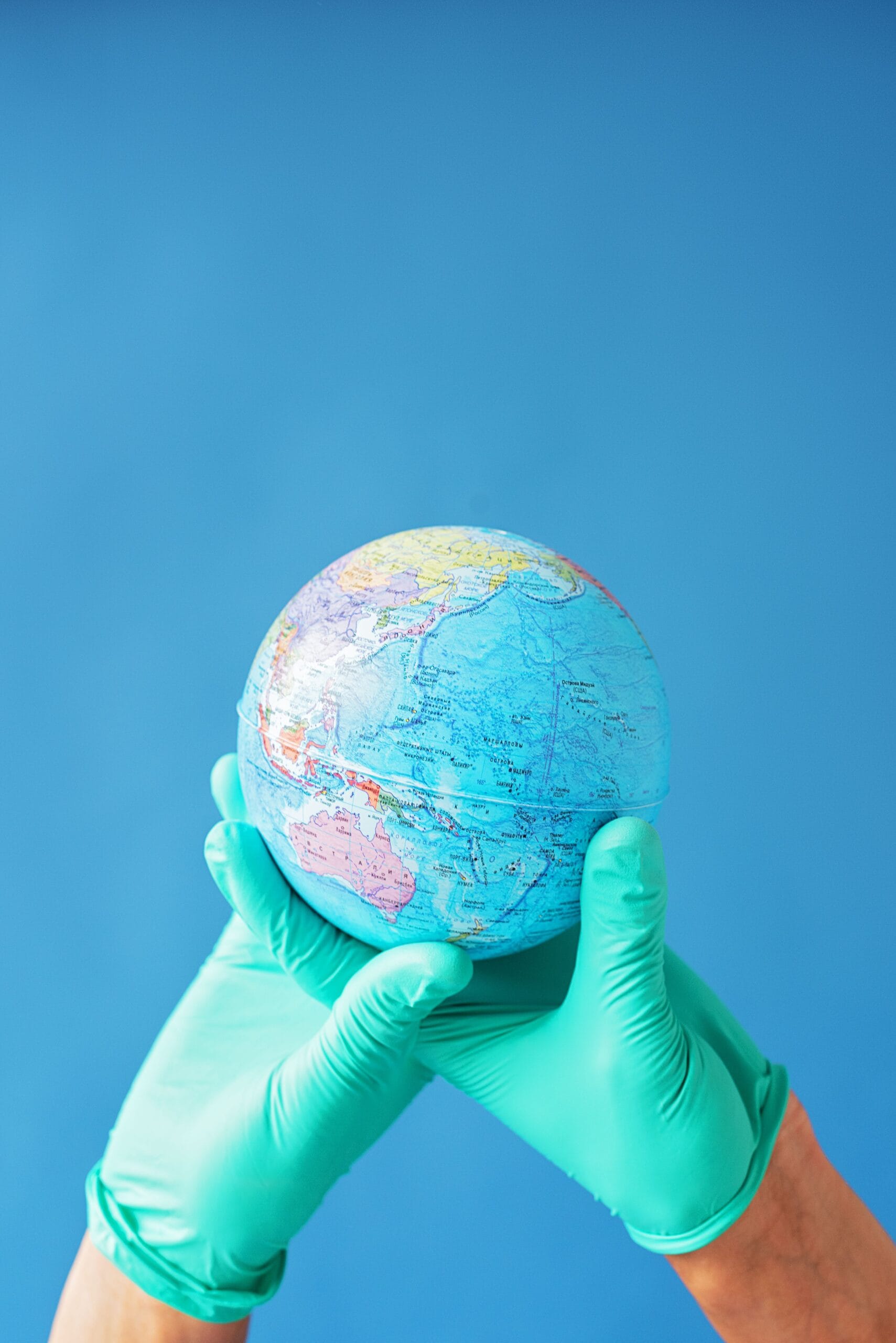 Medicare Reciprocal Health Care Agreements: What They Cover and What They Don't, Hands in latex gloves holding a globe against a bright blue background, symbolizing global care.